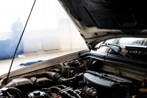 Detailed image of a car engine underneath the open hood in a well-lit indoor garage.